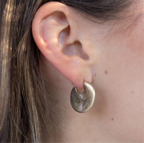 Picture of model wearing a textured gold disc earring.