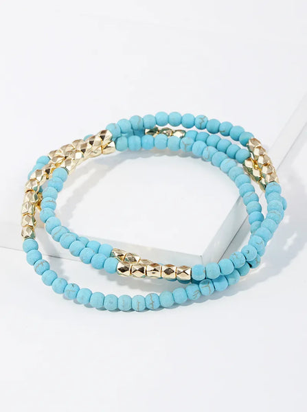 Set of three blue marble beaded bracelets in gold bead accents.