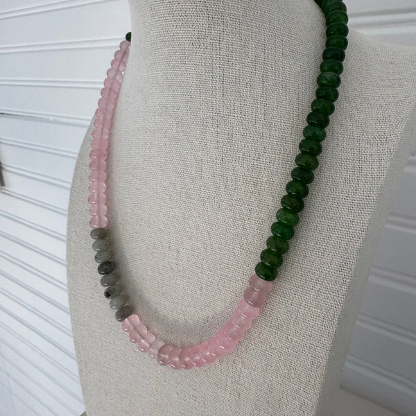 Necklace with dark green beads followed by clear pink beads, gray beads and then more pink beads.