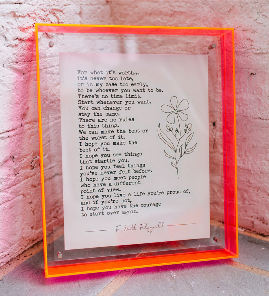 An orange/lit up clear frame with a book page inside it with a long typed quote and a line flower