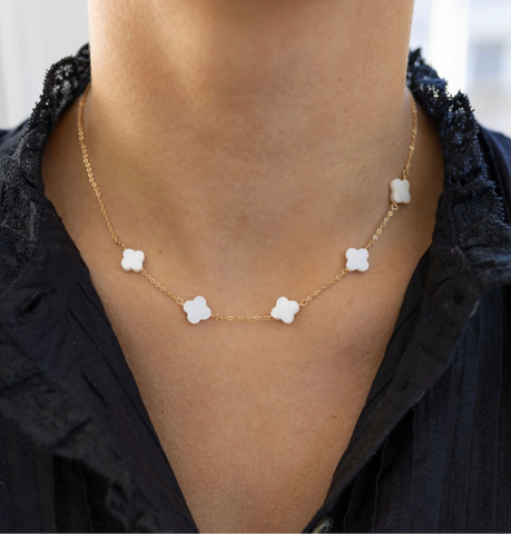 Model wearing a a gold chain with five white four clover flowers.