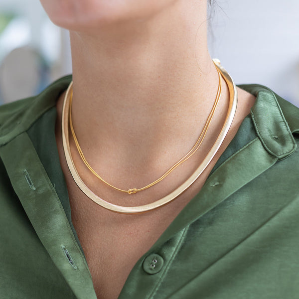 Woman wearing two gold necklaces 