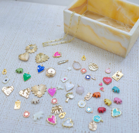 A wide selection of different charms next to a cream colored box