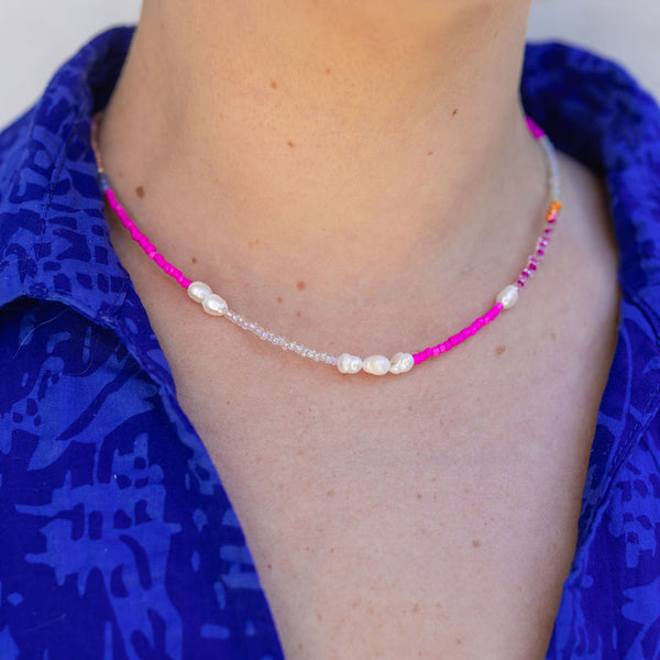 Woman wearing a short necklace/choker with bright pink beads and white pearls/stones
