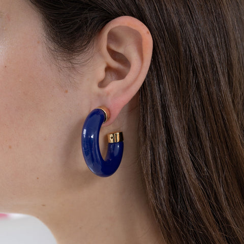 Picture of model wearing a dark blue chunky resin hoop earrings with gold accents.