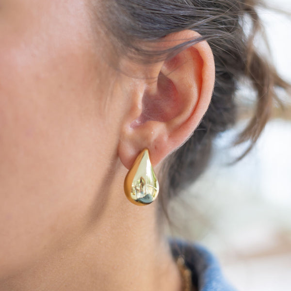 Woman wearing gold teardrop earrings