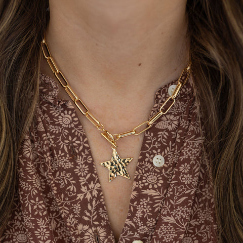 Model wearing gold chain necklace with a star pendant